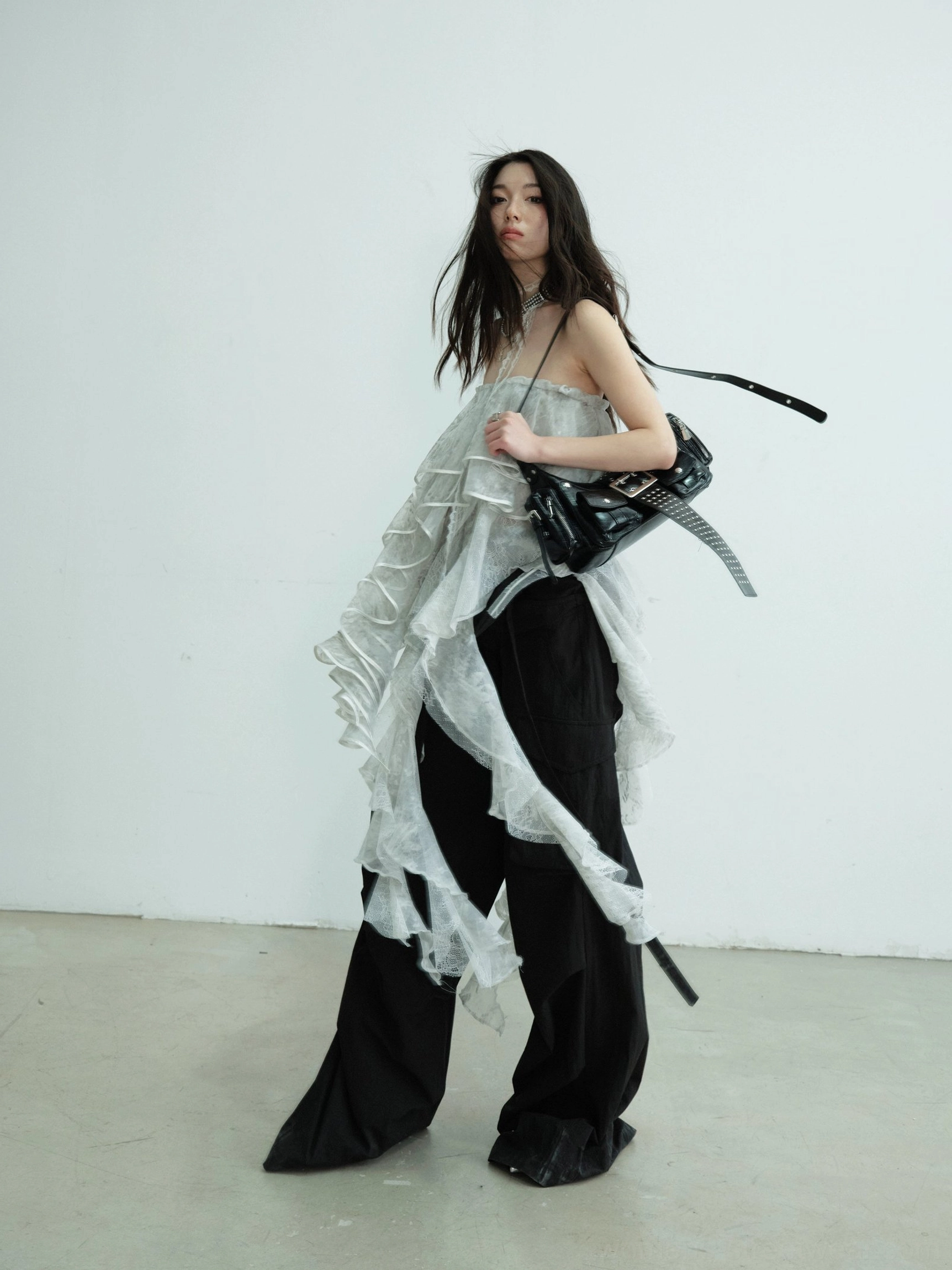 Side full body styling of a light gray sheer lace irregular ruffle tube top maxi skirt paired with relaxed black cargo pants