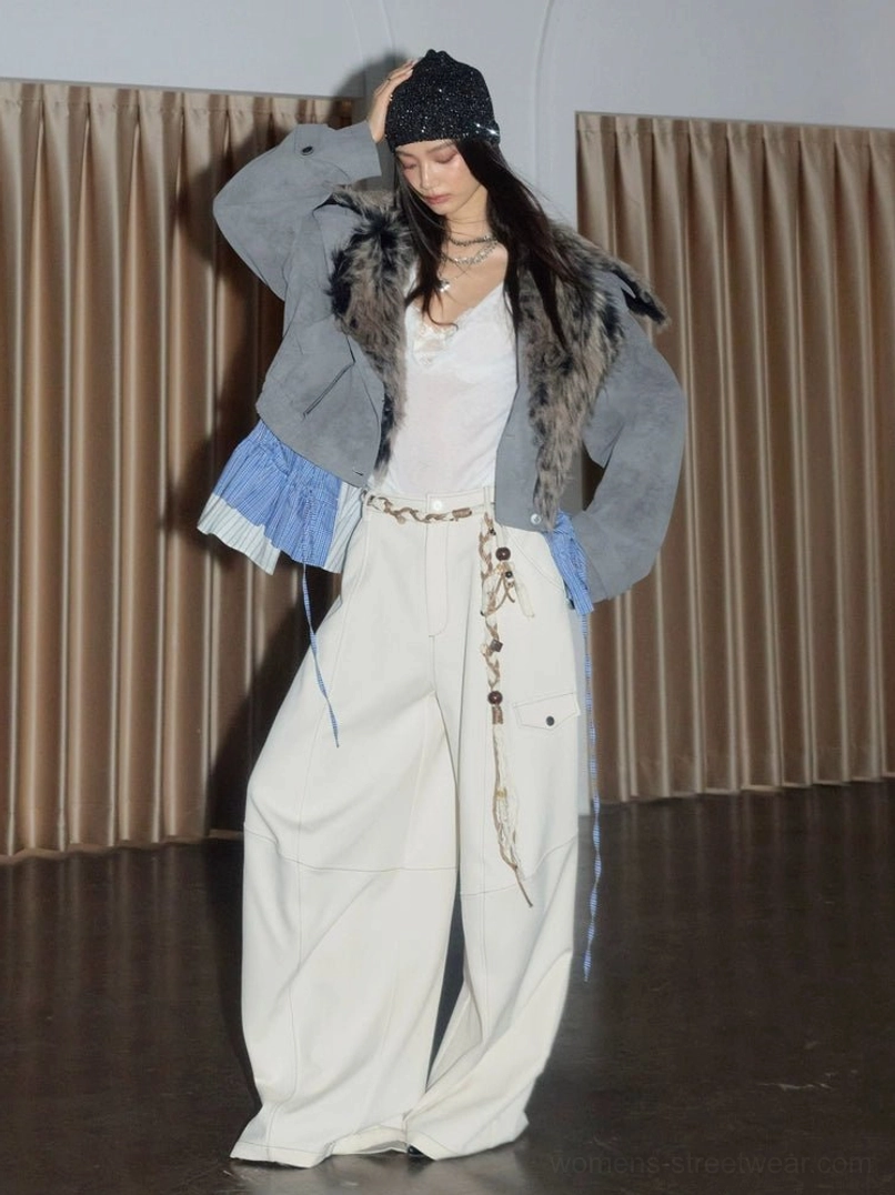 Side view of a light gray cropped faux suede jacket with faux fur collar adjustable hem detail and blue plaid ruffle worn with white cargo pants