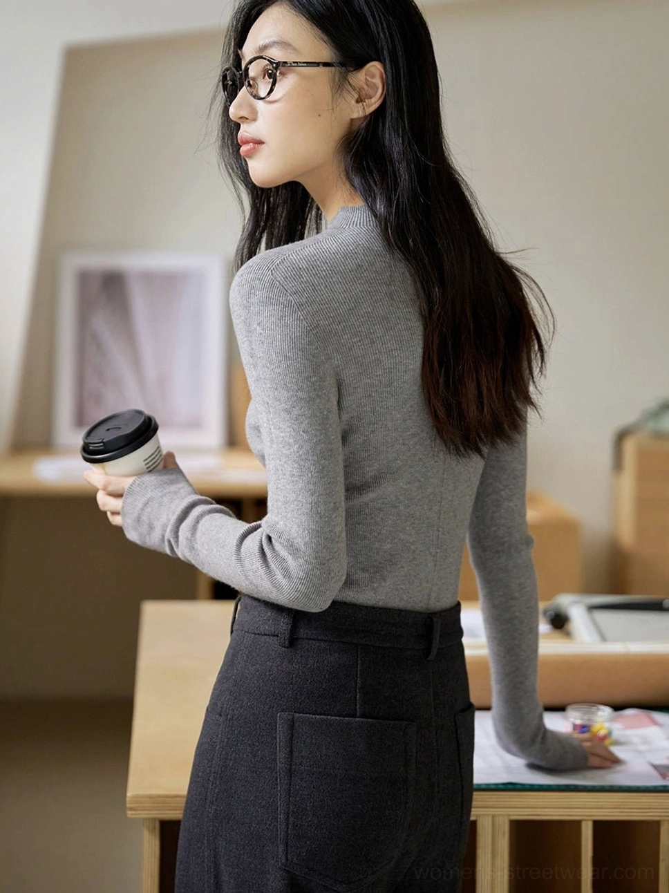 Light heather gray fitted mock neck knit sweater styled with dark high waisted pants in a minimalist home office