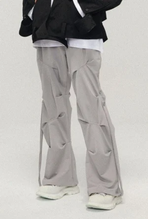 Light gray geo-sculpt wide-leg streetwear pants with crumpled pleats and side drawstrings styled with a white top and platform sneakers