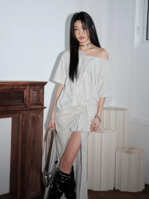 Light gray Korean streetwear maxi dress shown from the front with off-shoulder neckline, ruched waist, high leg slit, and silver chain handbag styling