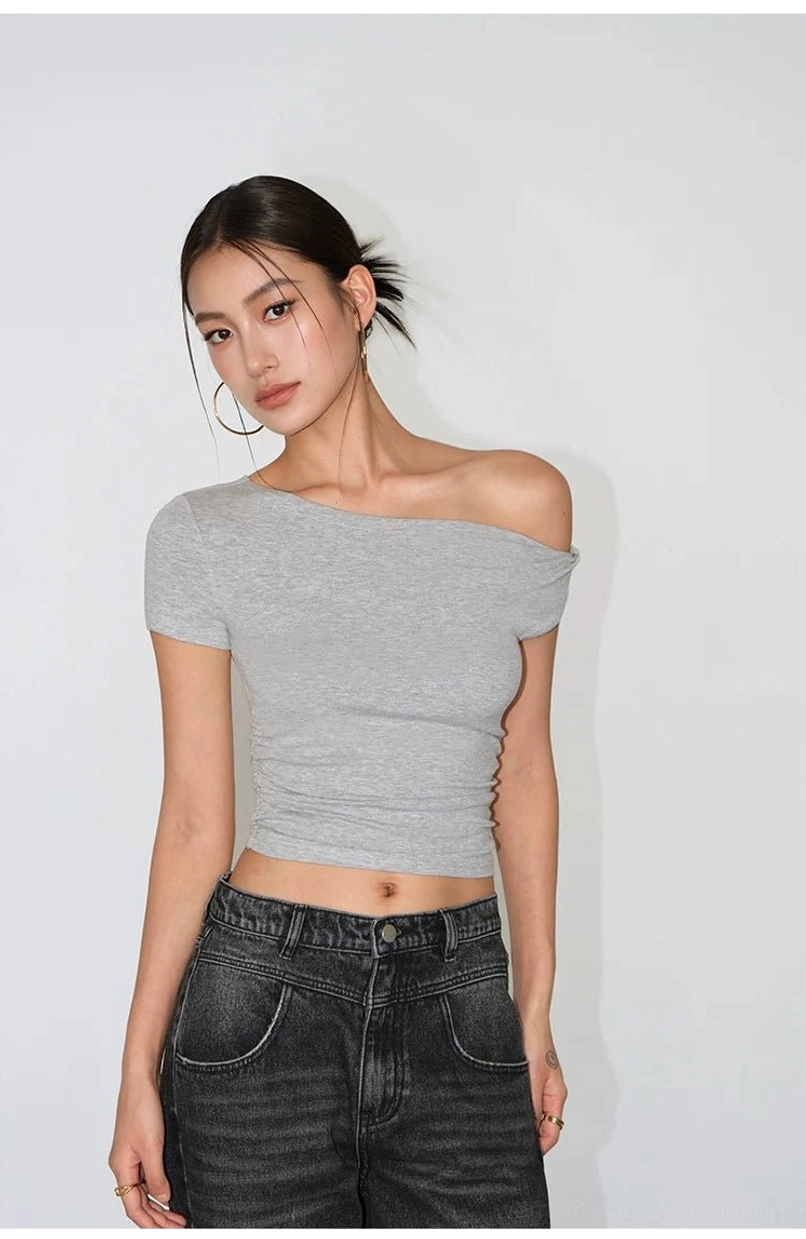 Light gray asymmetric one-shoulder cropped tee with a bare shoulder styled with black denim pants