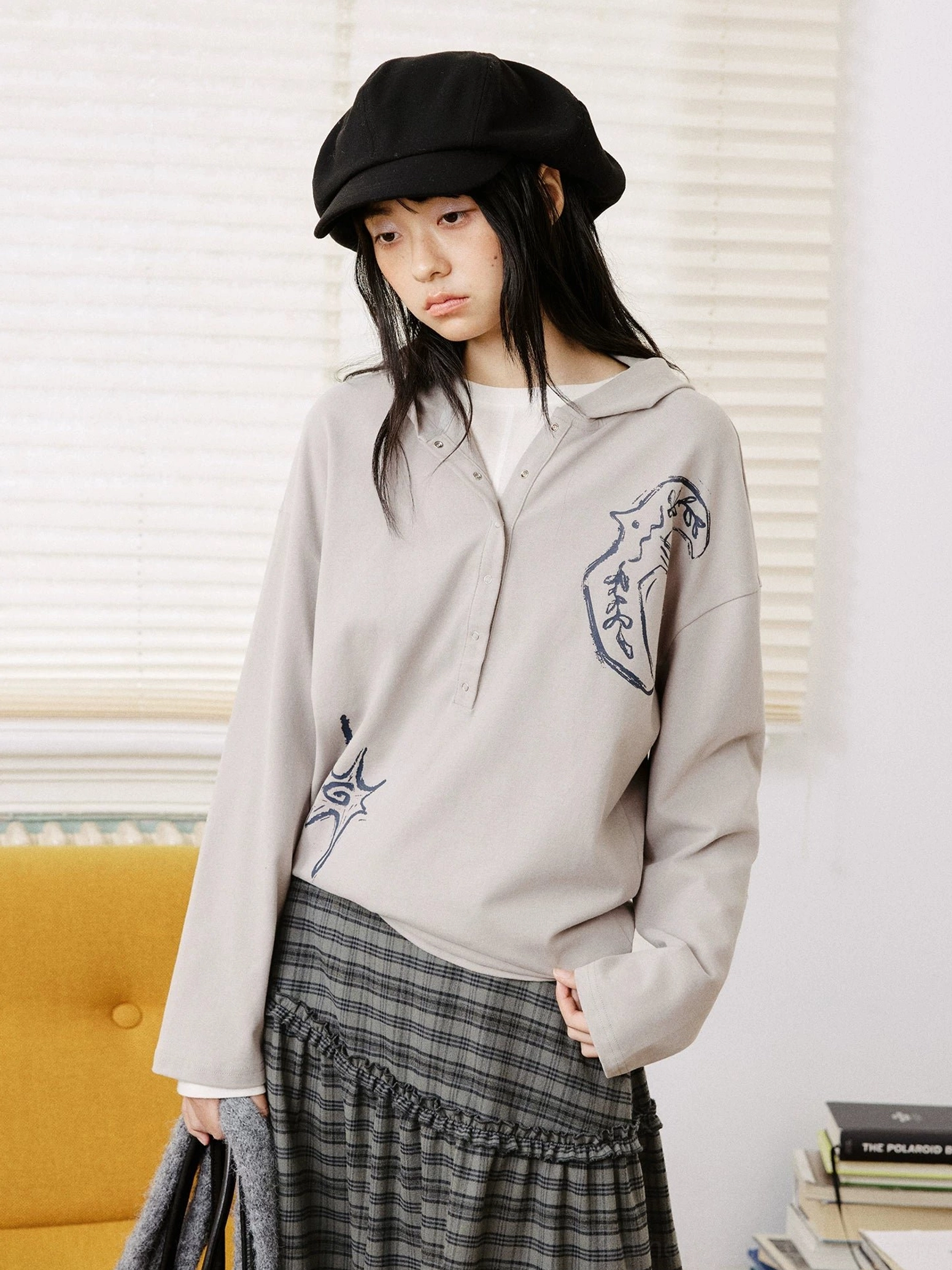 Light gray oversized embroidered graphic polo shirt styled with a plaid midi skirt in Korean streetwear fashion