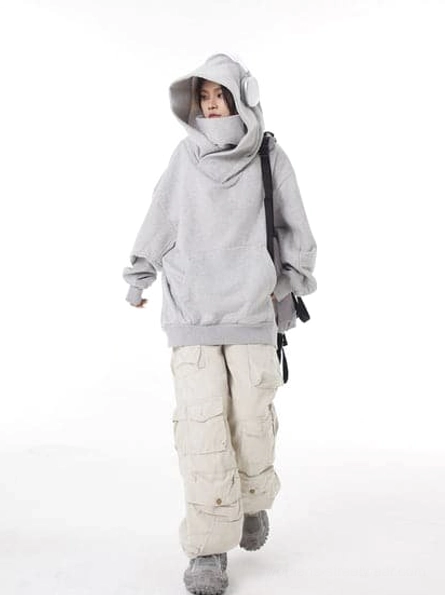 Light gray oversized high-neck hooded sweatshirt styled with beige cargo pants, gray sneakers, and playful ear-shaped hood details