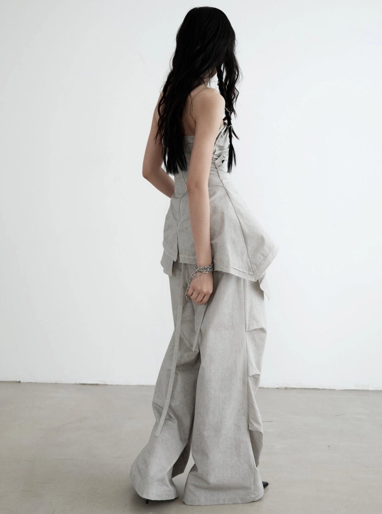 Rear view of light gray palazzo cargo pants highlighting the relaxed drape, structured ruffled waist, and oversized streetwear silhouette