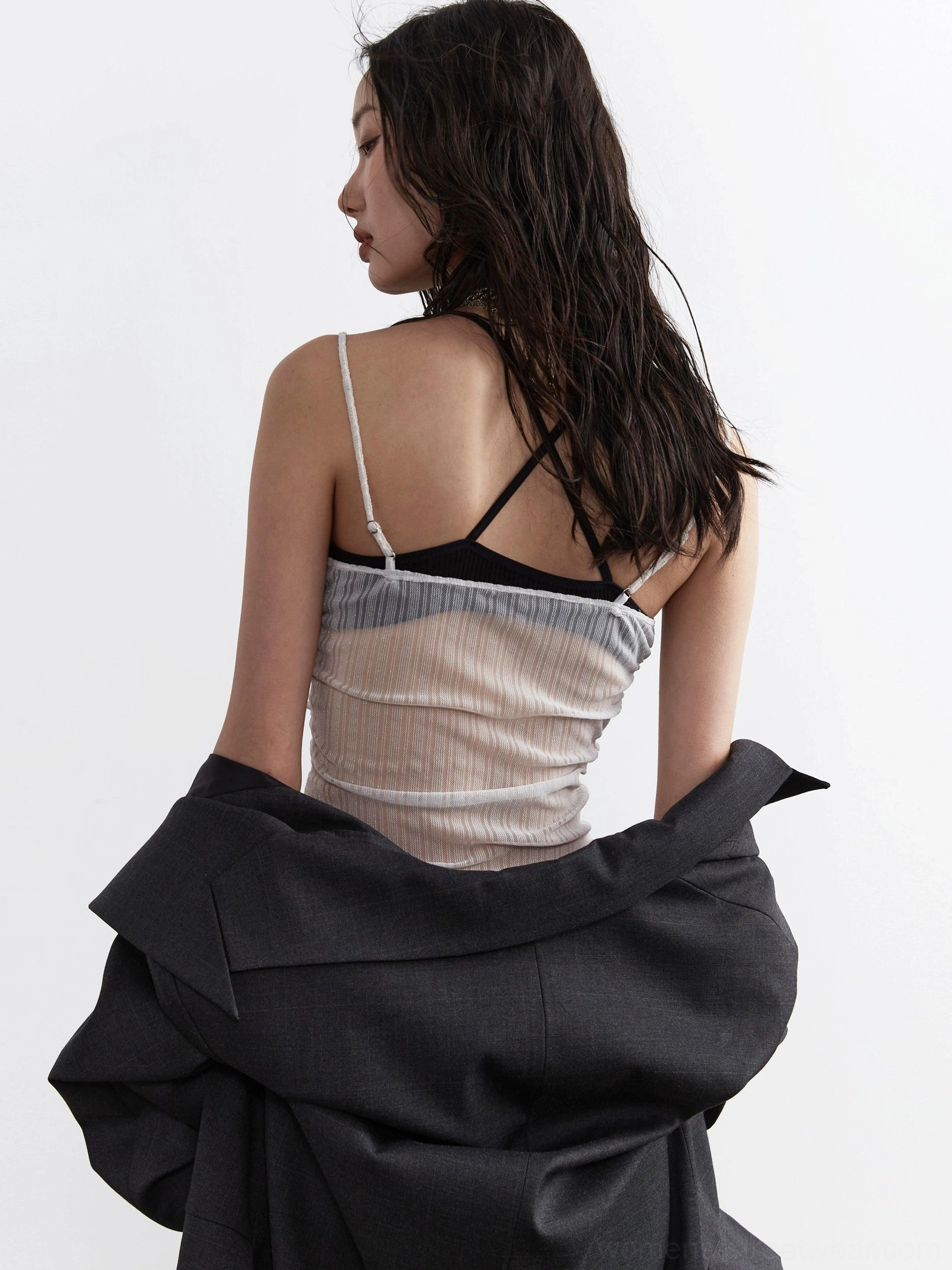 Back view of light gray sheer pleated corset top showing spaghetti straps translucent mesh panel and tulle ruffle hem