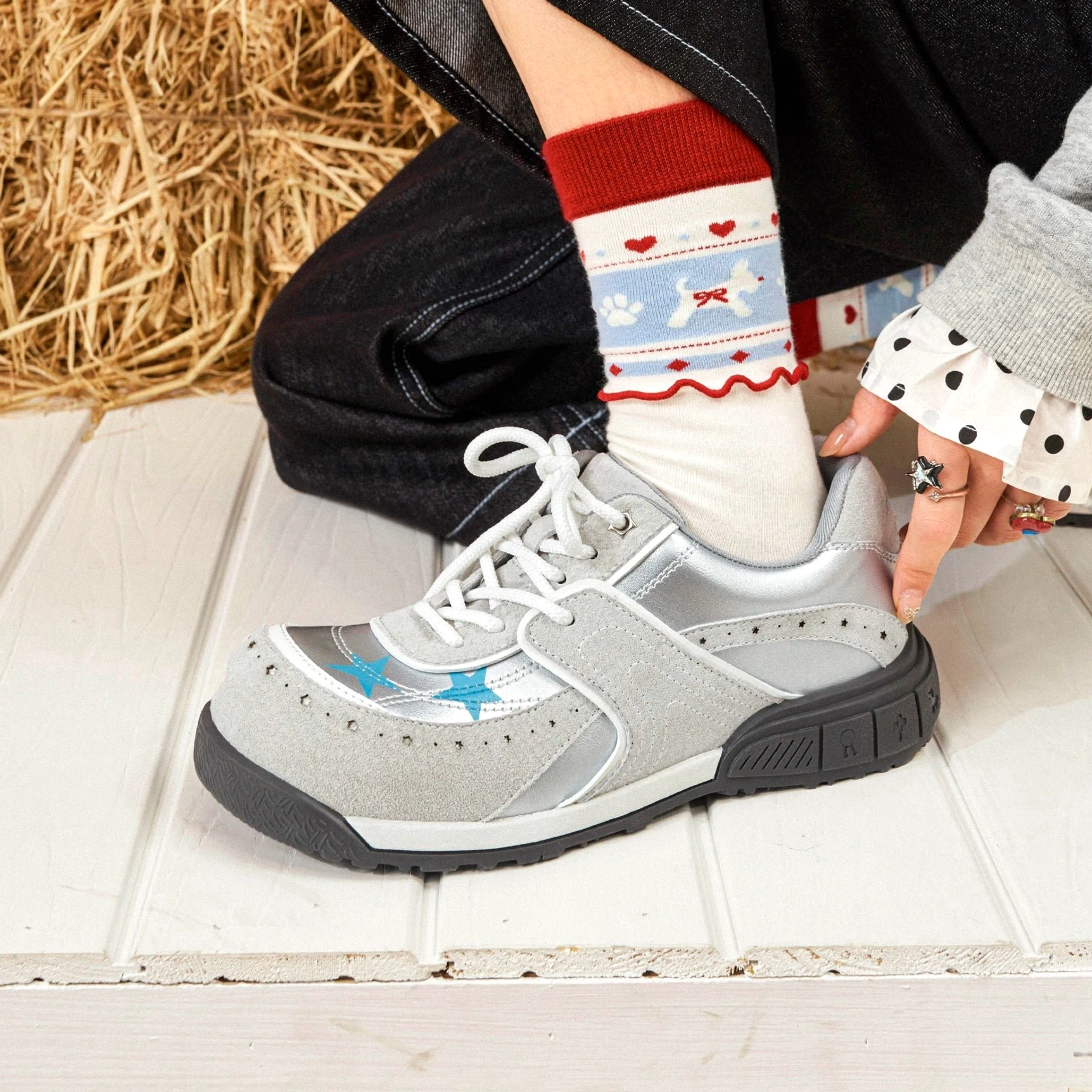 Light gray and silver star panel platform sneakers with blue star accents, chunky rubber sole, lace-up design, and streetwear styling worn with patterned socks