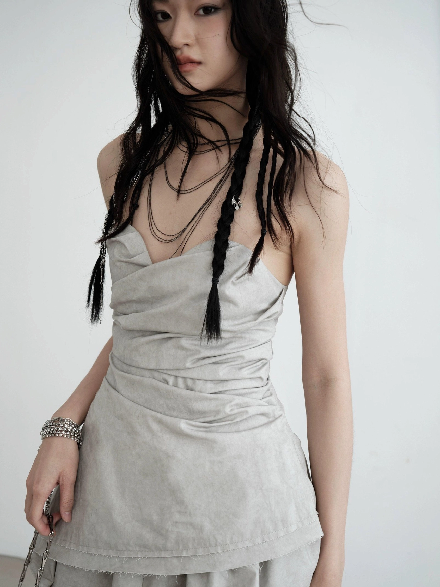 Close-up detail of light gray strapless ruched asymmetric draped top showing textured gathering and sweetheart neckline