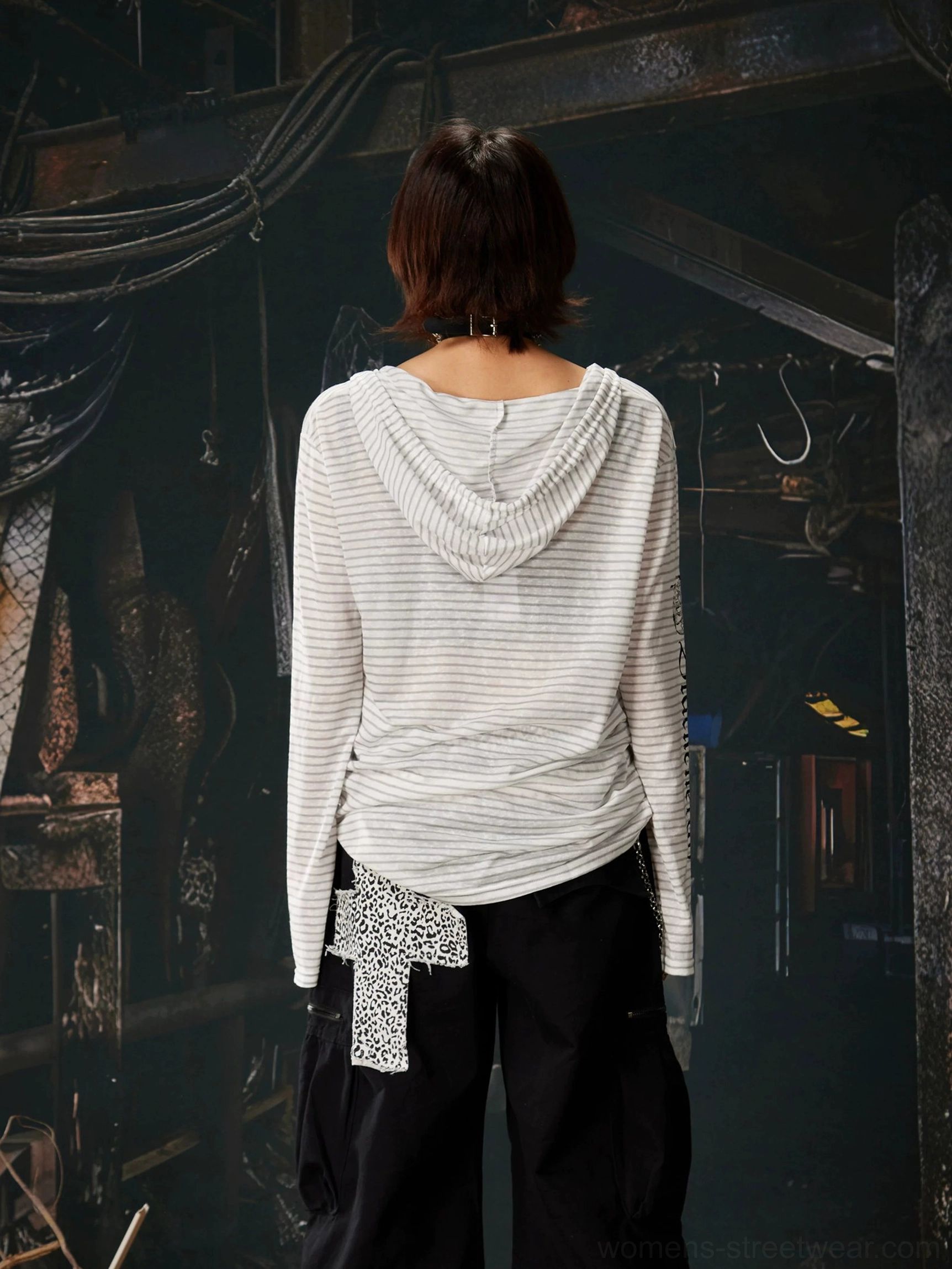 Back view of a light gray striped hooded long sleeve streetwear top with fixed drawstrings, styled with black cargo pants
