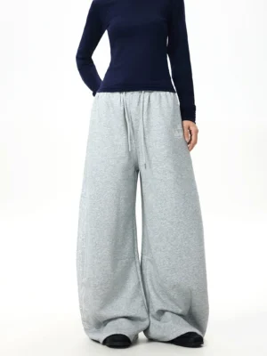 Front view of light gray ultra-wide-leg streetwear sweatpants with elastic drawstring waist, subtle hip embroidery, and oversized Korean fashion silhouette
