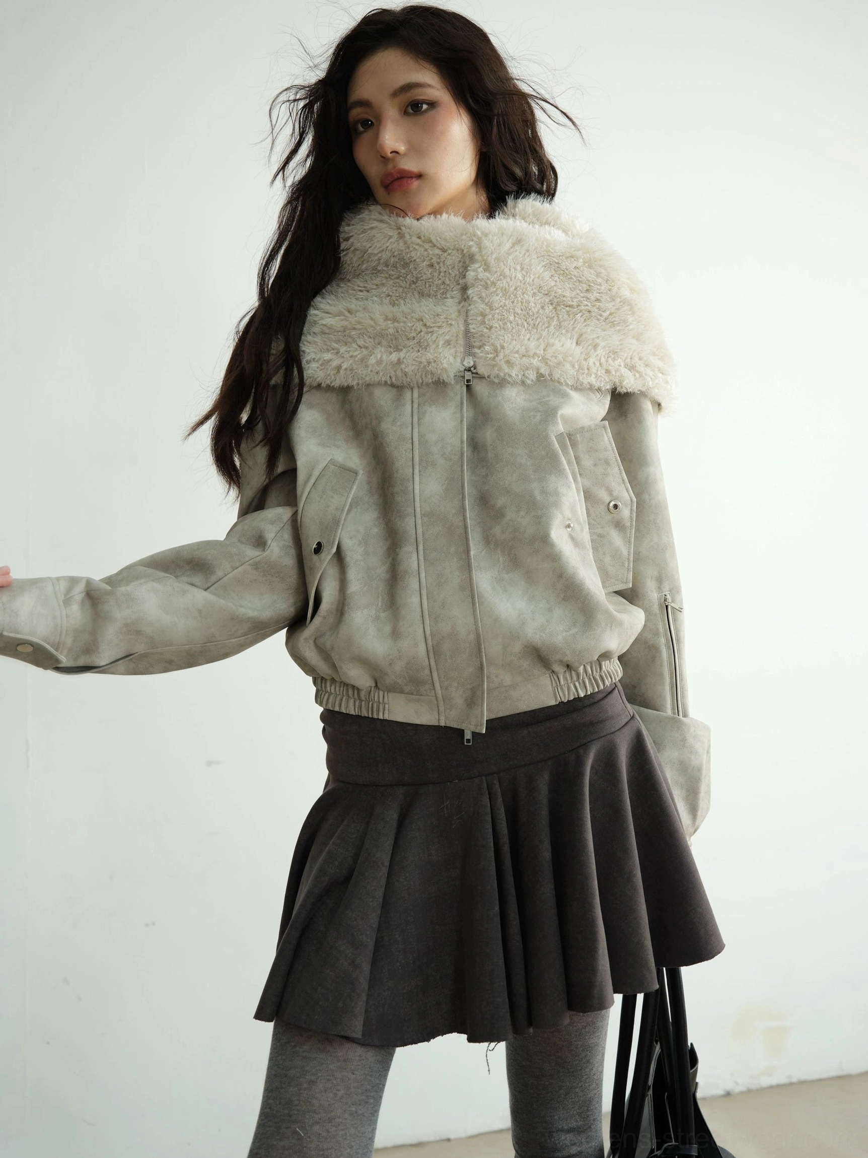 Front close-up of a light grey faux shearling hooded jacket showing faded suede-effect exterior, silver zipper, and wide fur collar