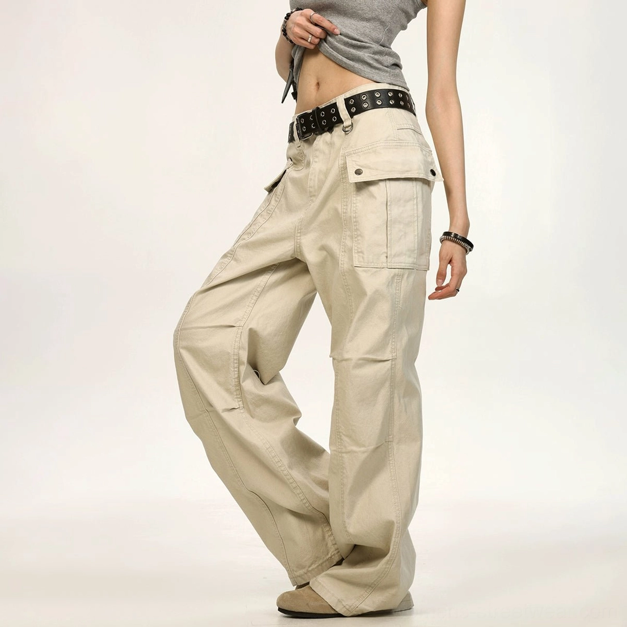 Light khaki beige relaxed canvas cargo pants shown from a three-quarter right side view with a large front flap pocket, loose utility silhouette, and textured fabric creases