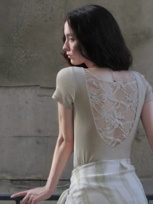 Back three-quarter view of a light khaki sheer embroidered back blouse with floral butterfly-inspired lace panel and fitted short-sleeve silhouette