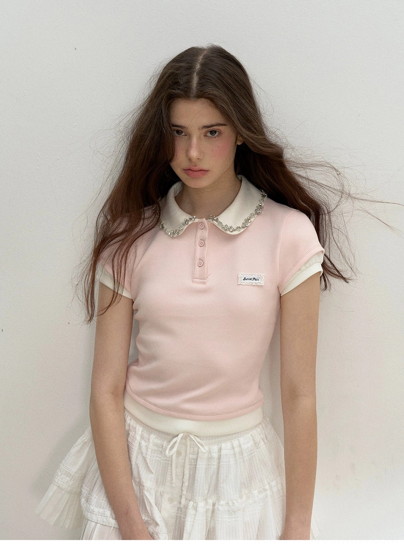 Close-up front view of light pink lace collar cotton polo top with contrast cuffs and embroidered chest detail