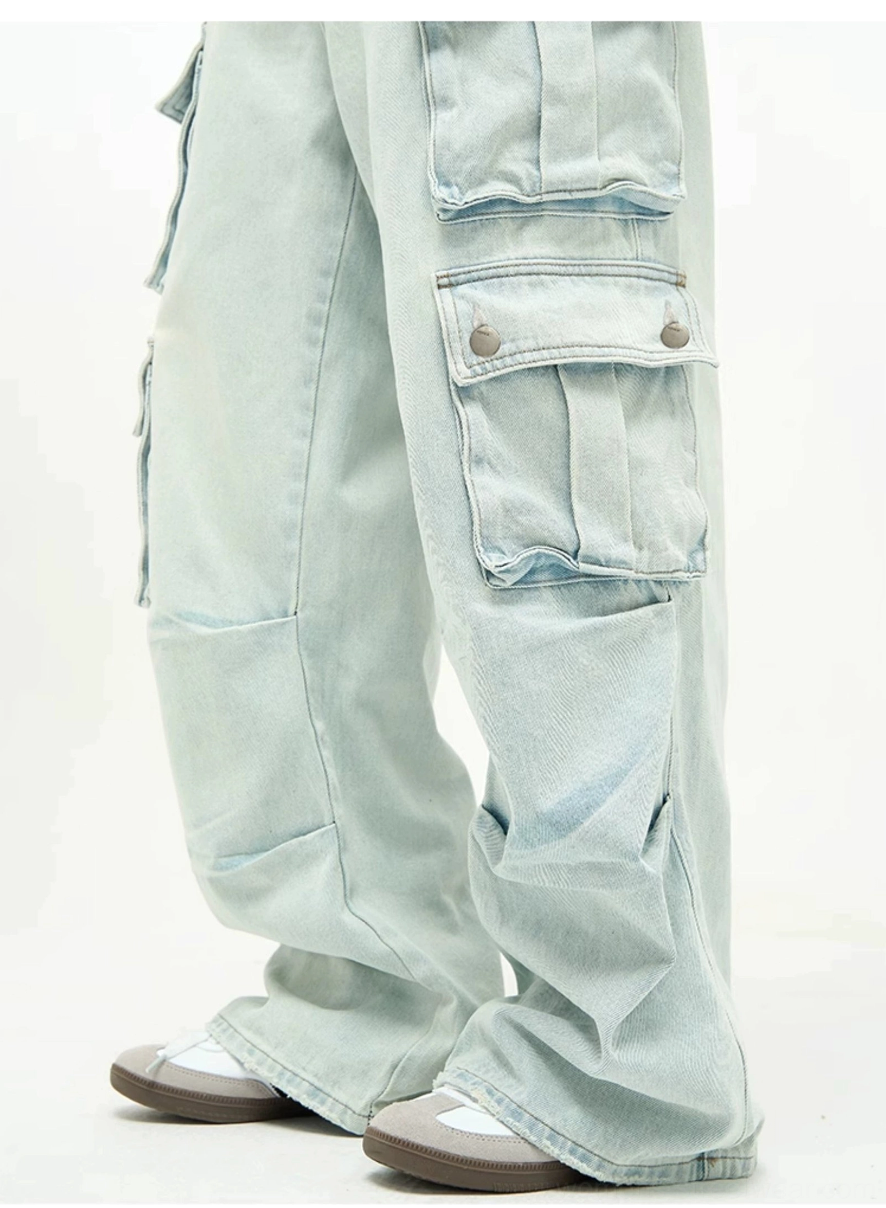 Light wash baggy cargo jeans with high-rise waist, extra-wide legs, multiple utility flap pockets, and contemporary streetwear denim design