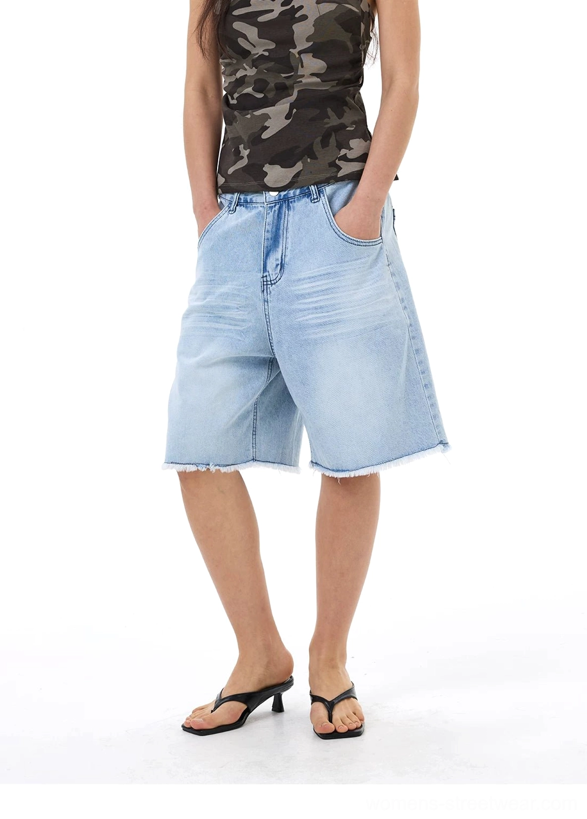 Full front view of high-volume light wash denim Bermuda shorts with a faded blue finish, loose silhouette, and raw cut hems