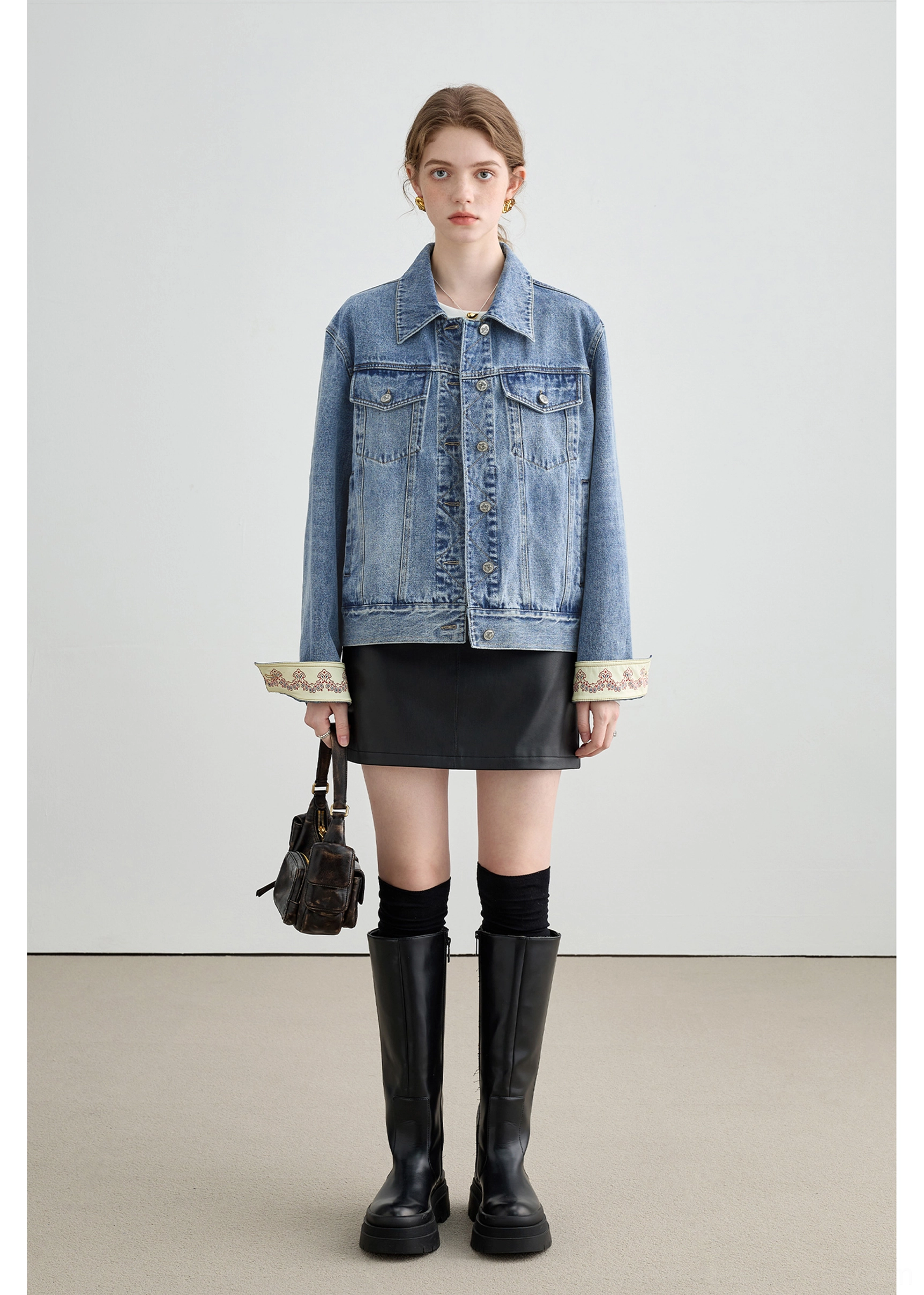 Full body streetwear outfit featuring a light wash denim jacket, black mini skirt, platform knee-high boots, and mini handbag