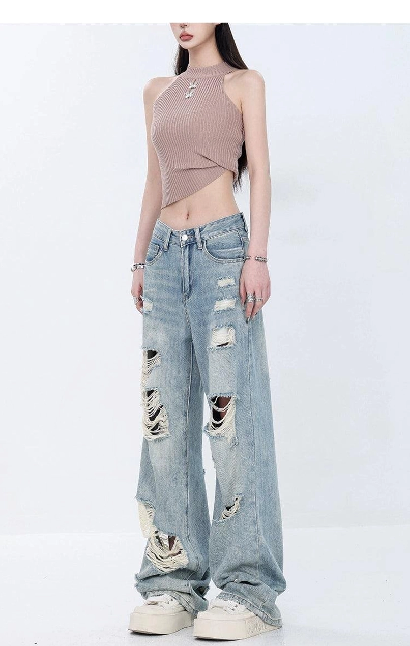 Angled front view of distressed light wash wide-leg jeans with ripped thighs, torn knees, and high-waist denim fit