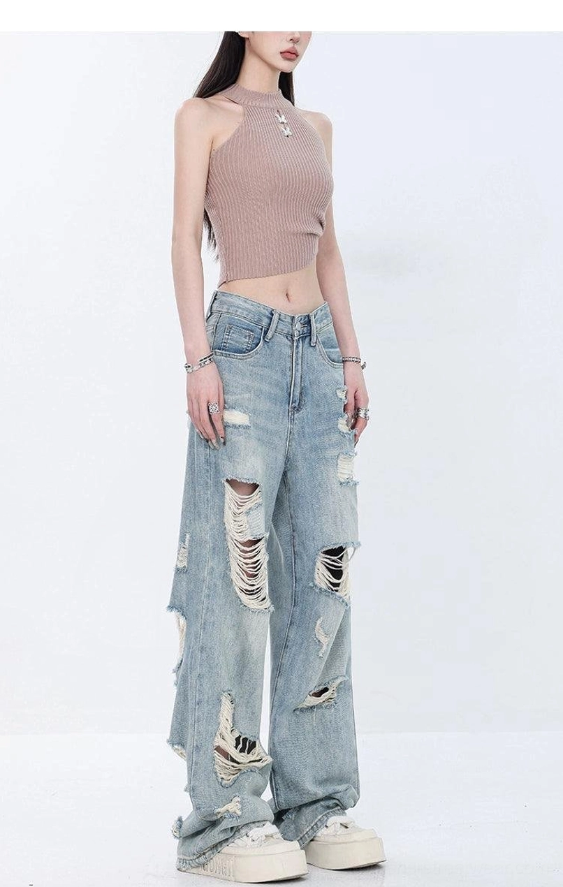 Angled full-body view of high-waist light wash grunge jeans with dramatic ripped knees and wide-leg silhouette