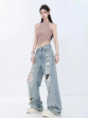 Front full-body view of light wash distressed high-waist wide-leg grunge jeans styled with a taupe halter crop top and white platform sneakers