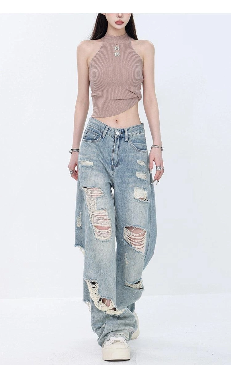 Low-angle walking view of heavily ripped light wash high-waist wide-leg grunge jeans paired with white platform sneakers