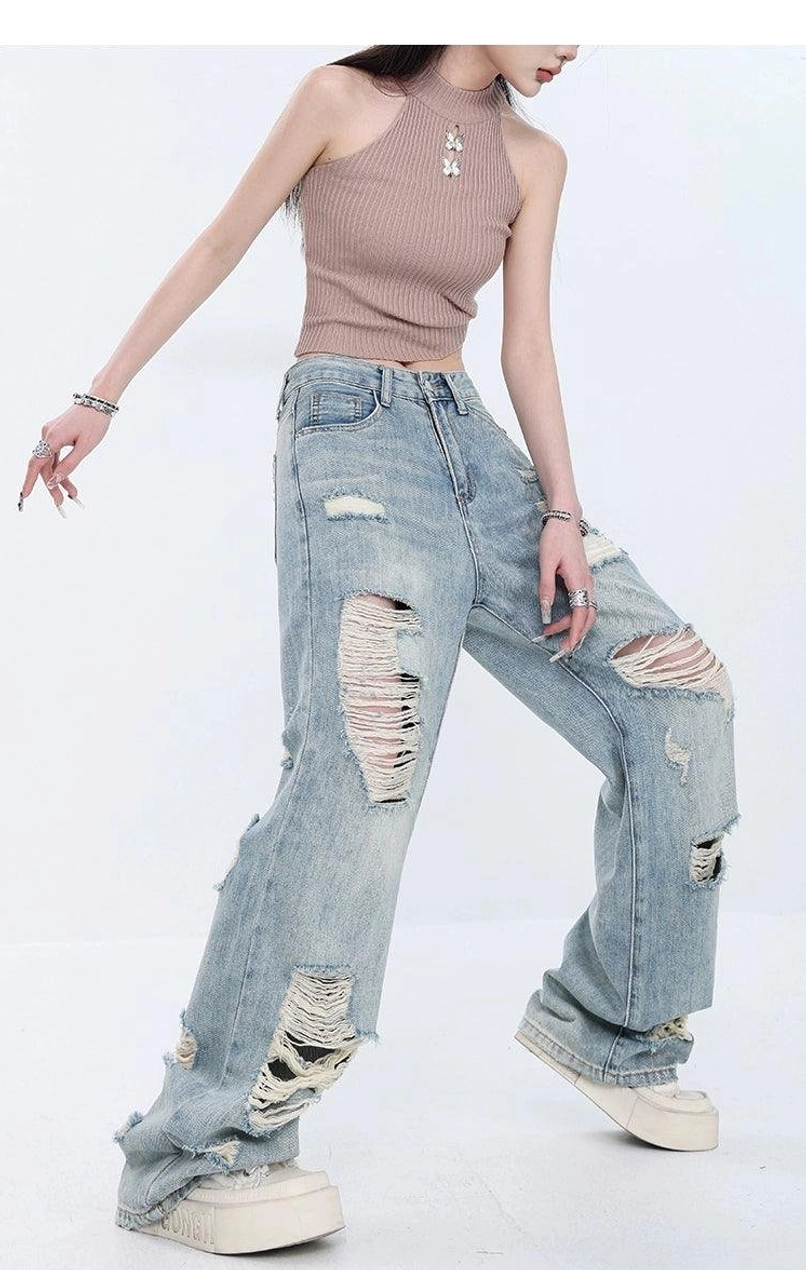 Side walking view of heavily distressed light blue high-waist wide-leg jeans with ripped thigh and knee details