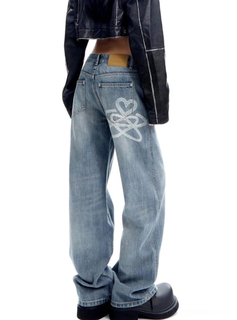 Rear view of light wash wide-leg denim jeans featuring heart-loop embroidery on the back pocket and a yellow leather waistband tag