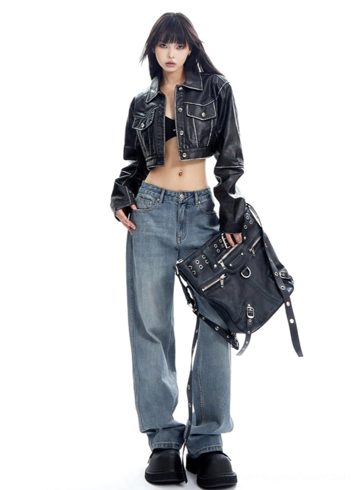 Front three-quarter streetwear styling of light wash wide-leg jeans with a cropped leather jacket, black bralette, and studded biker handbag
