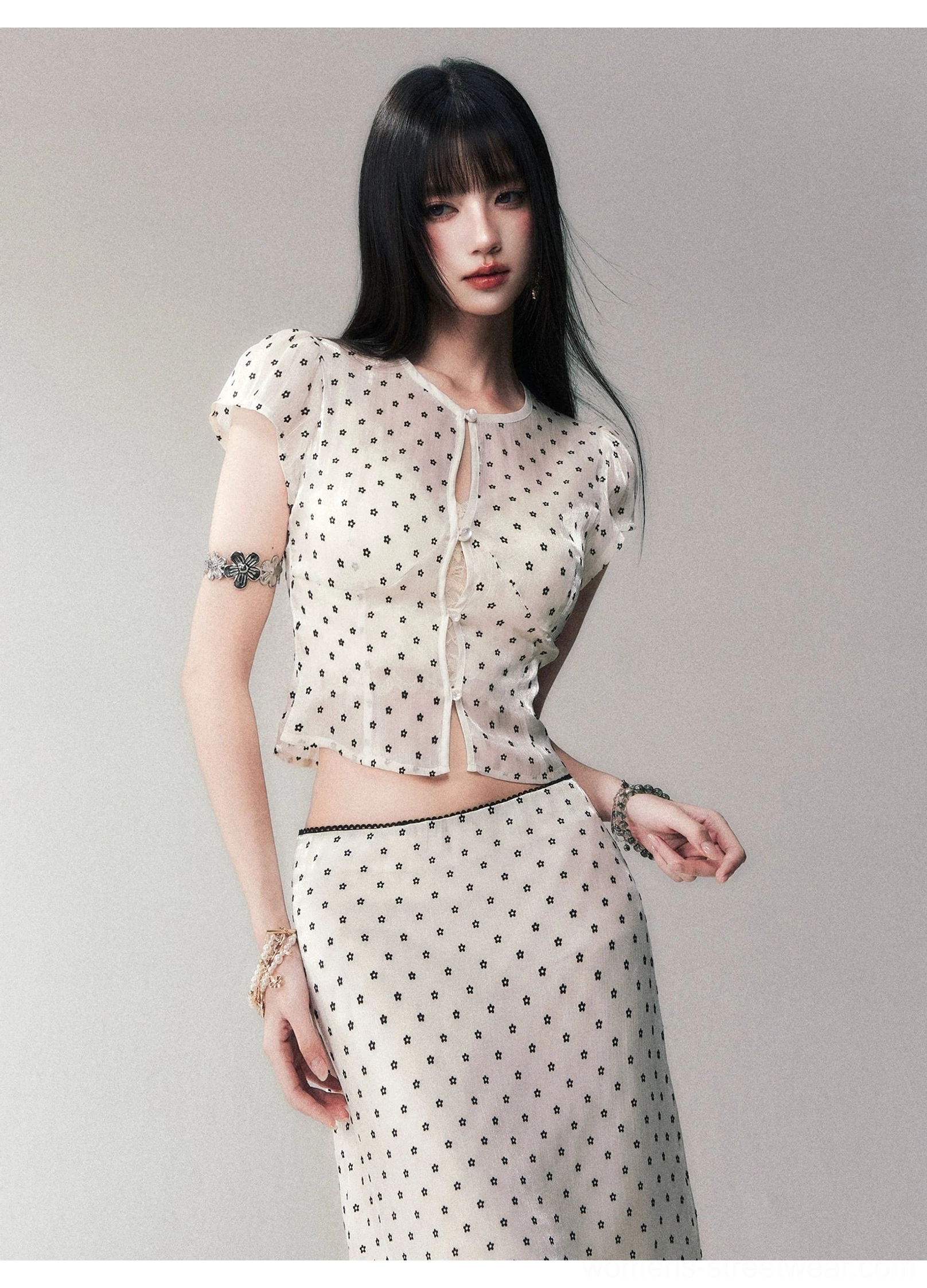 Close side detail of lightweight beige mesh fabric with black polka dots on fitted crop top and midi skirt