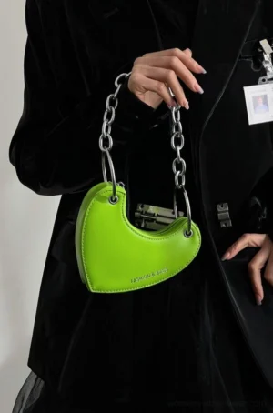 Lime green heart-shaped chain mini bag held with black tailored streetwear outfit