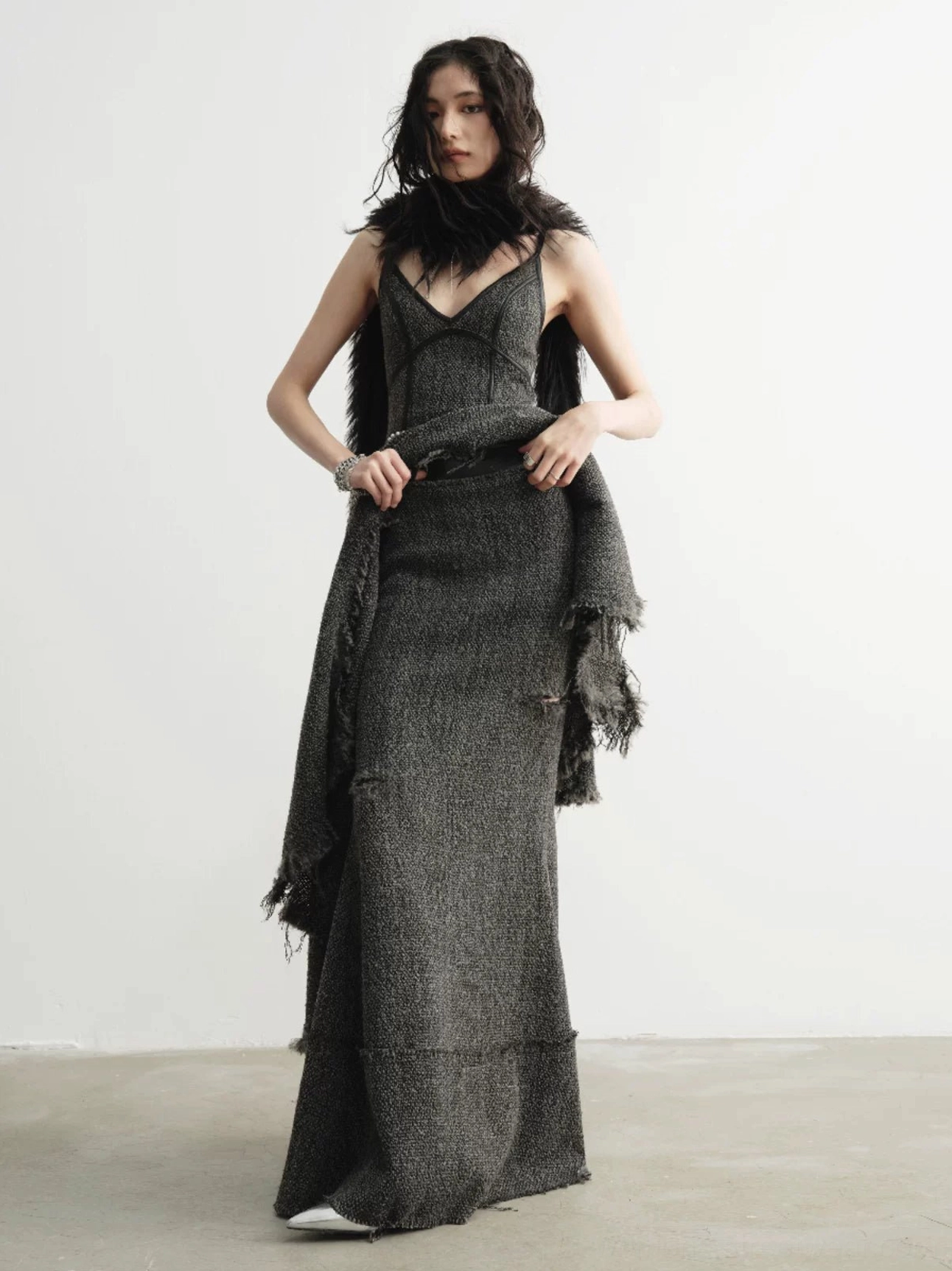 Side view of long distressed tweed fishtail skirt showing its fitted hip silhouette and floor-length flared hem