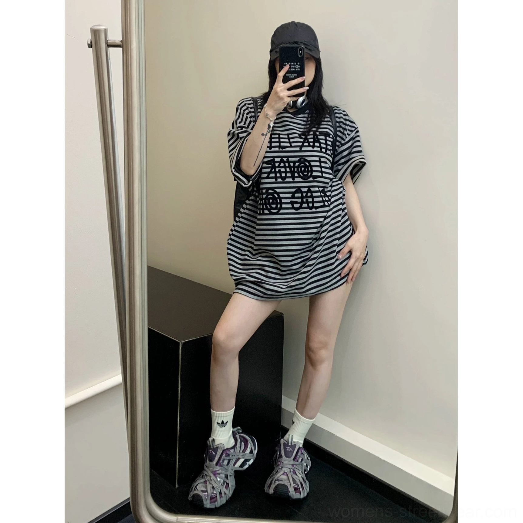 Full-body front view of a longline oversized black striped graphic tee with raised lettering styled with sporty sneakers