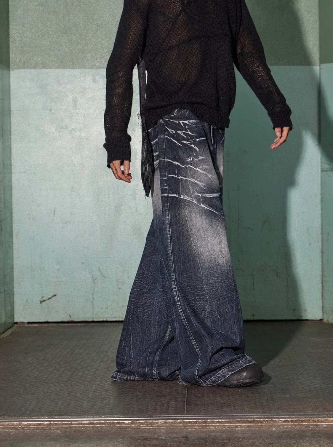 Front three-quarter view of loose baggy dark indigo jeans with an electric lightning wash pattern