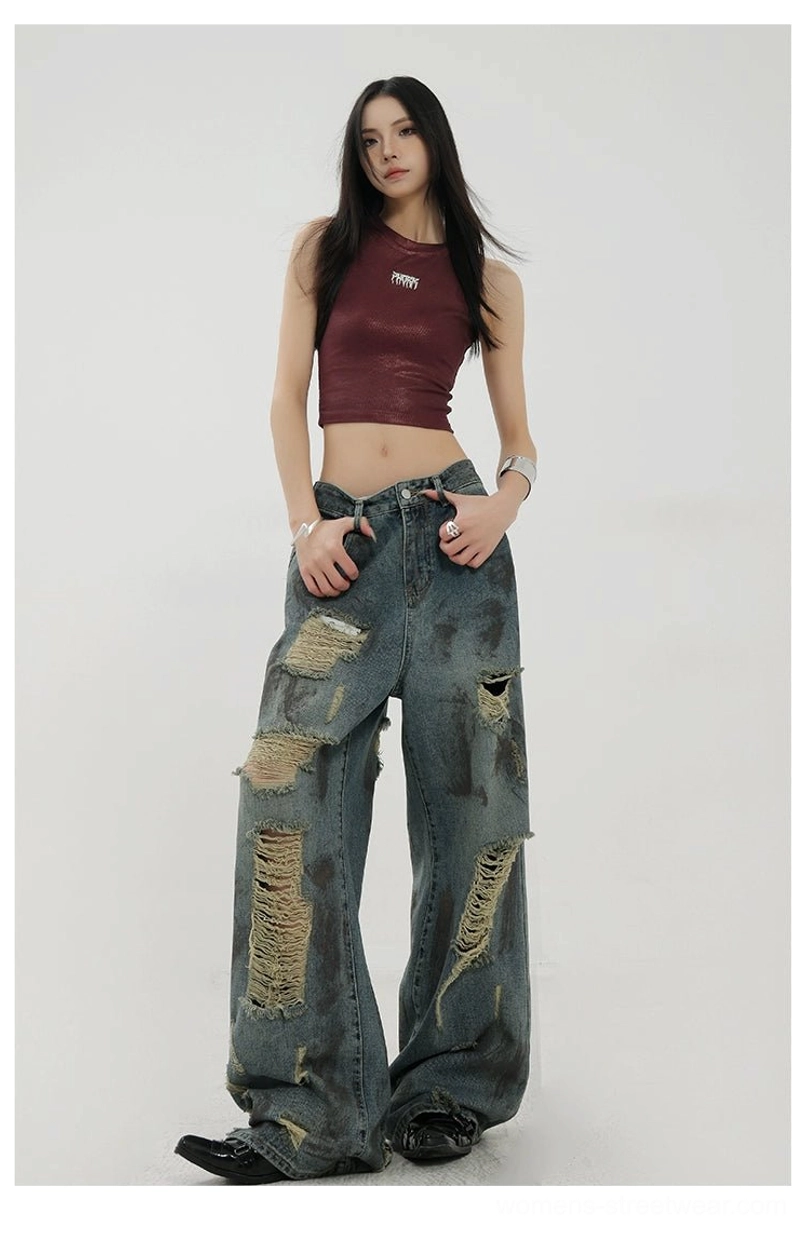 Side standing view of high-volume loose blue wide-leg jeans with multiple destroyed holes and vintage faded denim