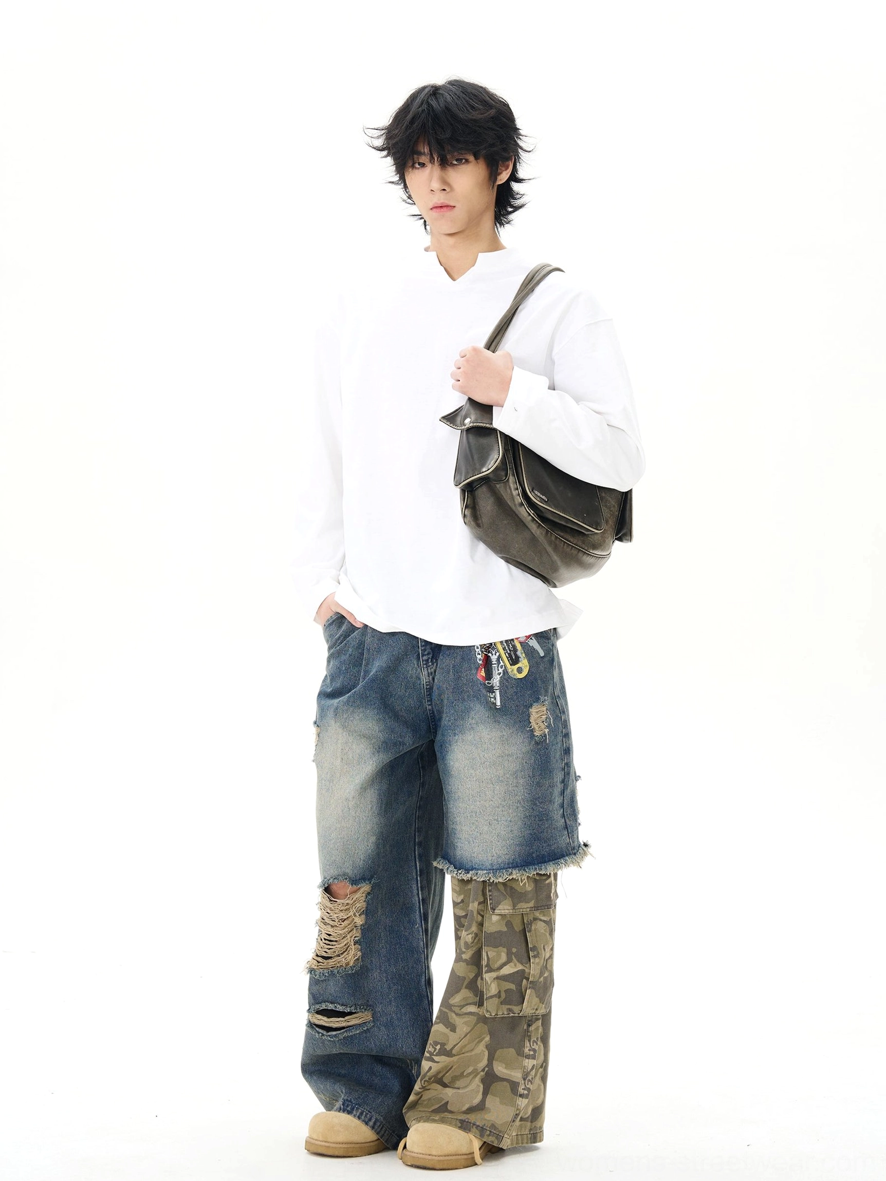 Front view of loose distressed patchwork wide-leg jeans styled with a crossbody bag, featuring washed blue denim, camo cargo patchwork, and frayed ripped accents