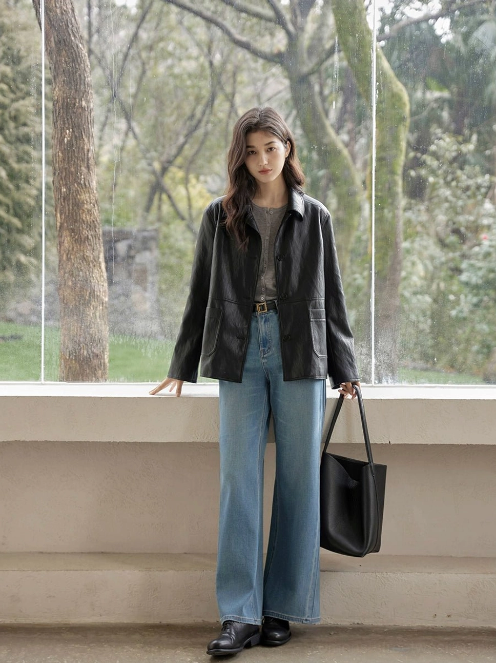 Woman wearing a loose fit vintage black leather jacket with long sleeves in an indoor streetwear outfit