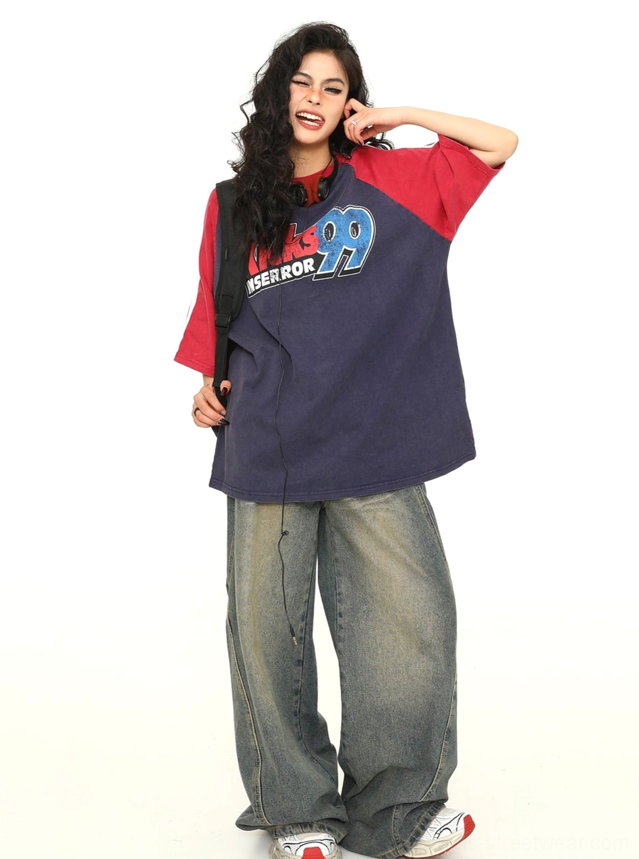 Female streetwear model wearing a loose navy and red retro varsity graphic tee with wide-leg jeans