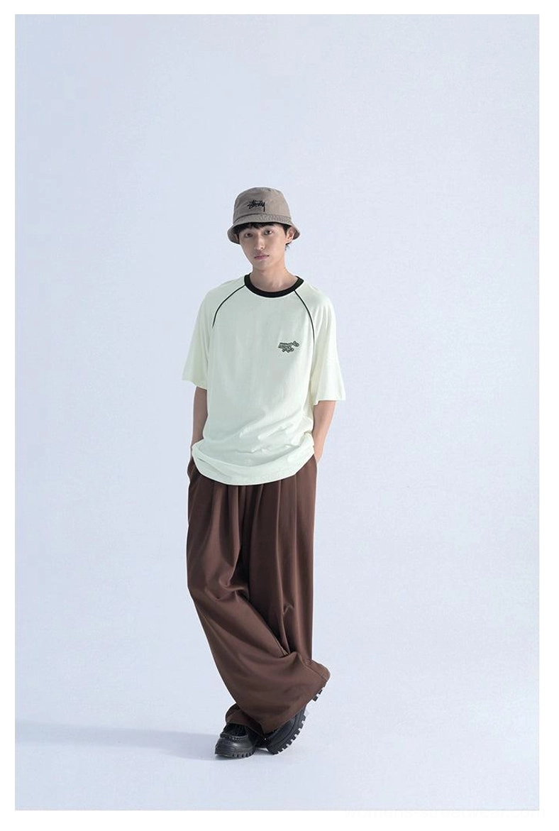 Front view of loose raglan sleeve logo T-shirt styled with wide-leg trousers, contrast collar, embroidered chest detail, and Korean streetwear aesthetic