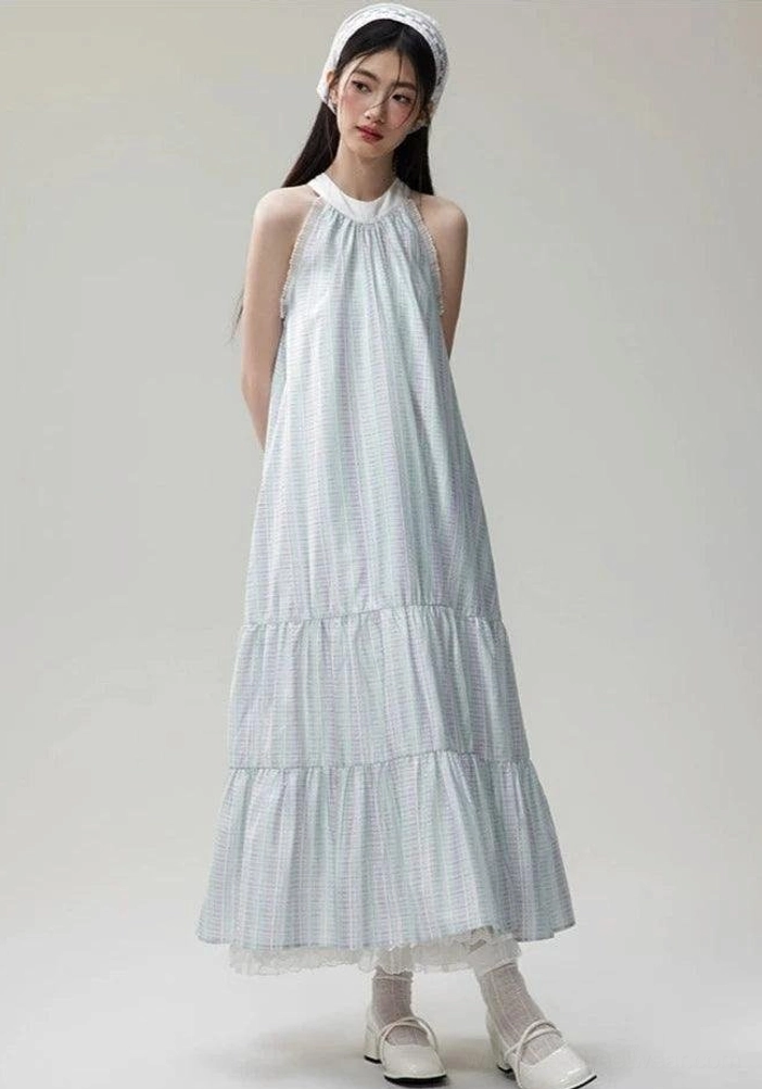 Full front view of a loose sleeveless halter maxi dress with light gingham pattern, airy organza layers, matching headband, flat shoes, and frilled socks