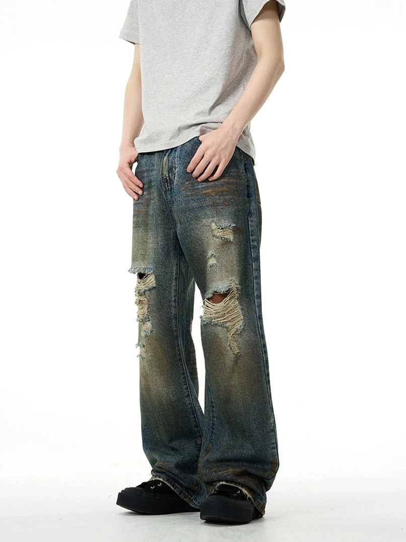 Side rear view of loose wide-leg distressed denim jeans showing vintage blue wash, ripped knees, and relaxed streetwear fit