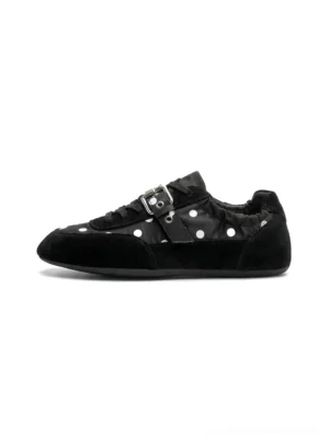 Black low-profile polka dot ballet sneakers with white dots, silver buckle strap, suede-look toe cap, and flat streetwear sole