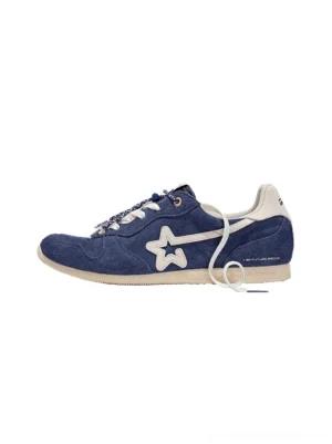 Navy blue low-profile retro suede panel sneakers with star-inspired side accents, white flat laces, and off-white rubber soles shown from the side