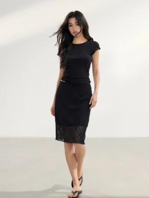 Front view of a fitted low-rise black midi skirt with sheer checked lace mesh hem styled with a black crop top