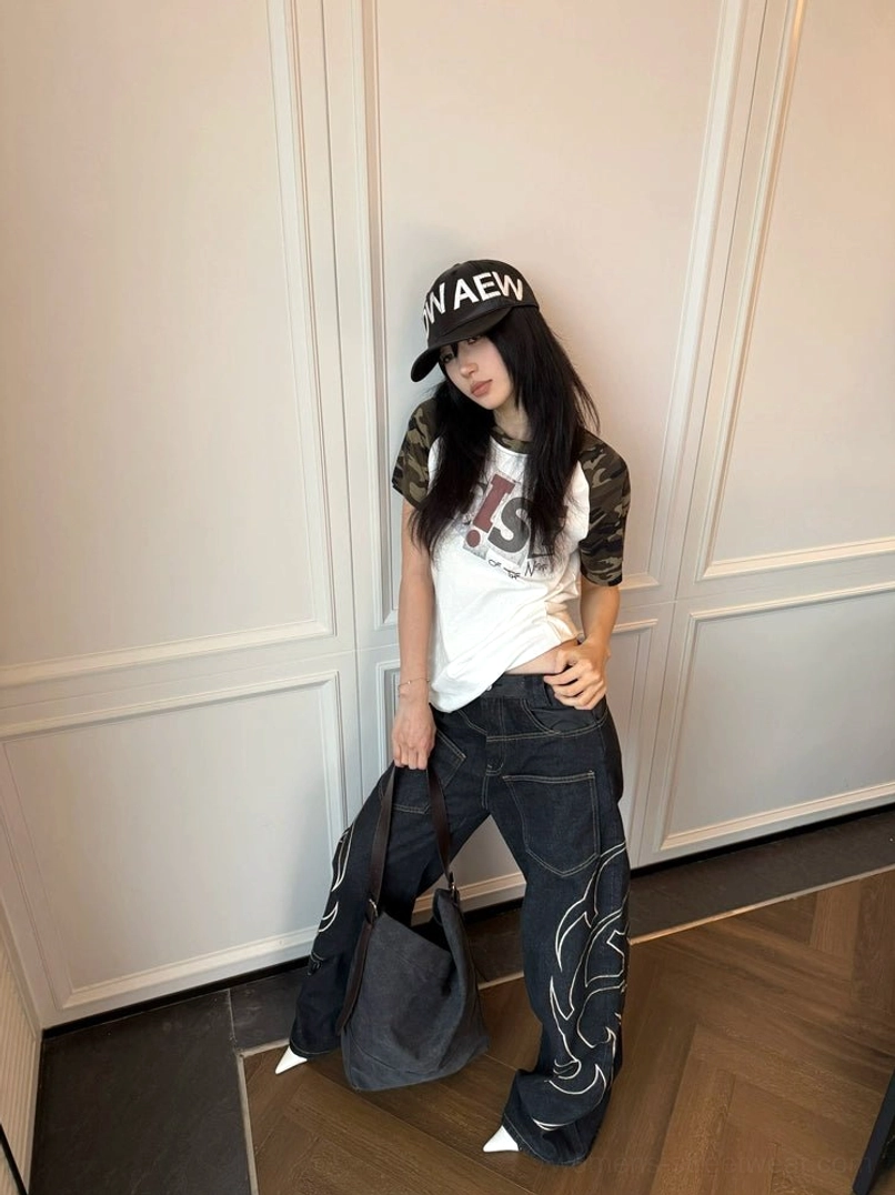 Full side view of low-rise black tribal embroidery jeans with ultra-wide legs and white flame graphics styled for Korean streetwear fashion