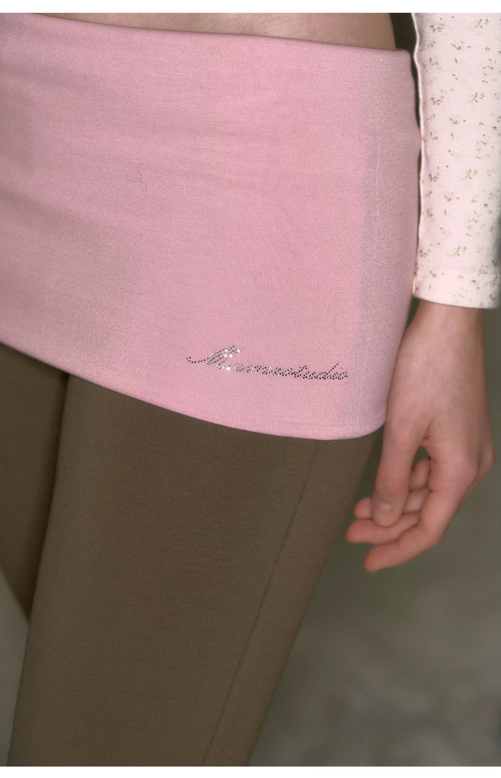 Close-up detail of pink fold-over waistband on khaki low-rise stretch micro flare yoga pants