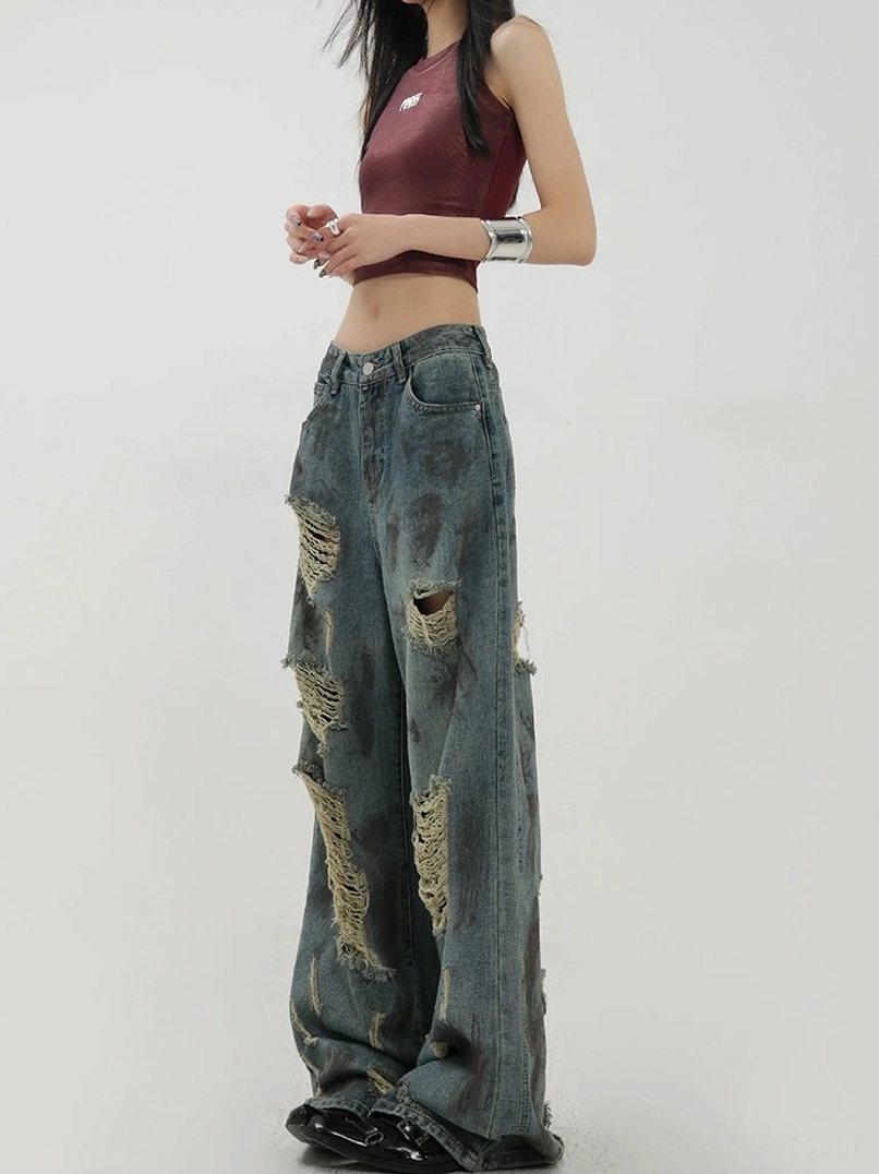 Side view showing the low-rise-inspired waist, loose draped leg silhouette, and frayed distressed details on blue denim jeans