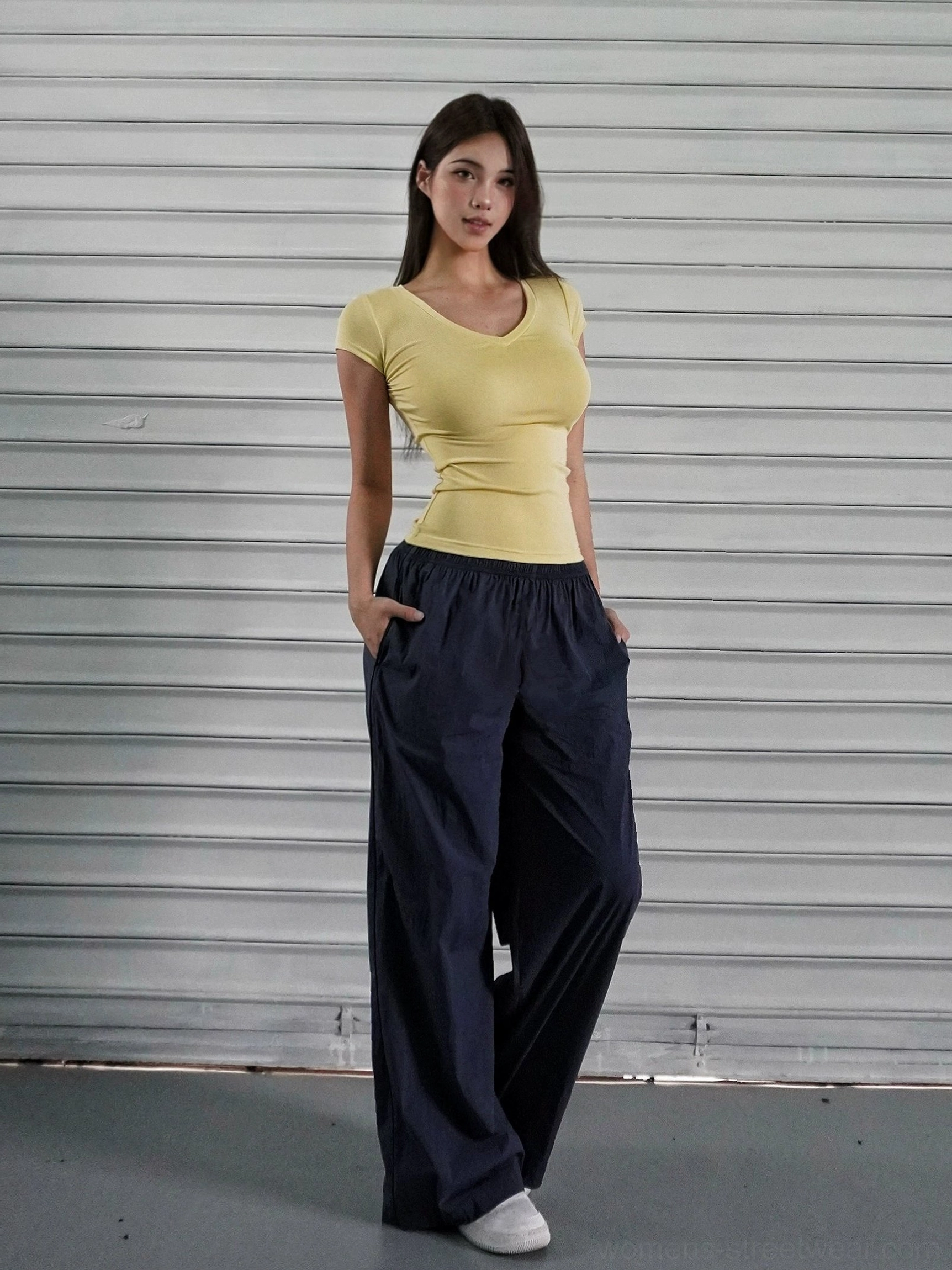 Navy blue low-rise wide-leg athletic cargo pants styled with a yellow cropped top in an industrial streetwear studio