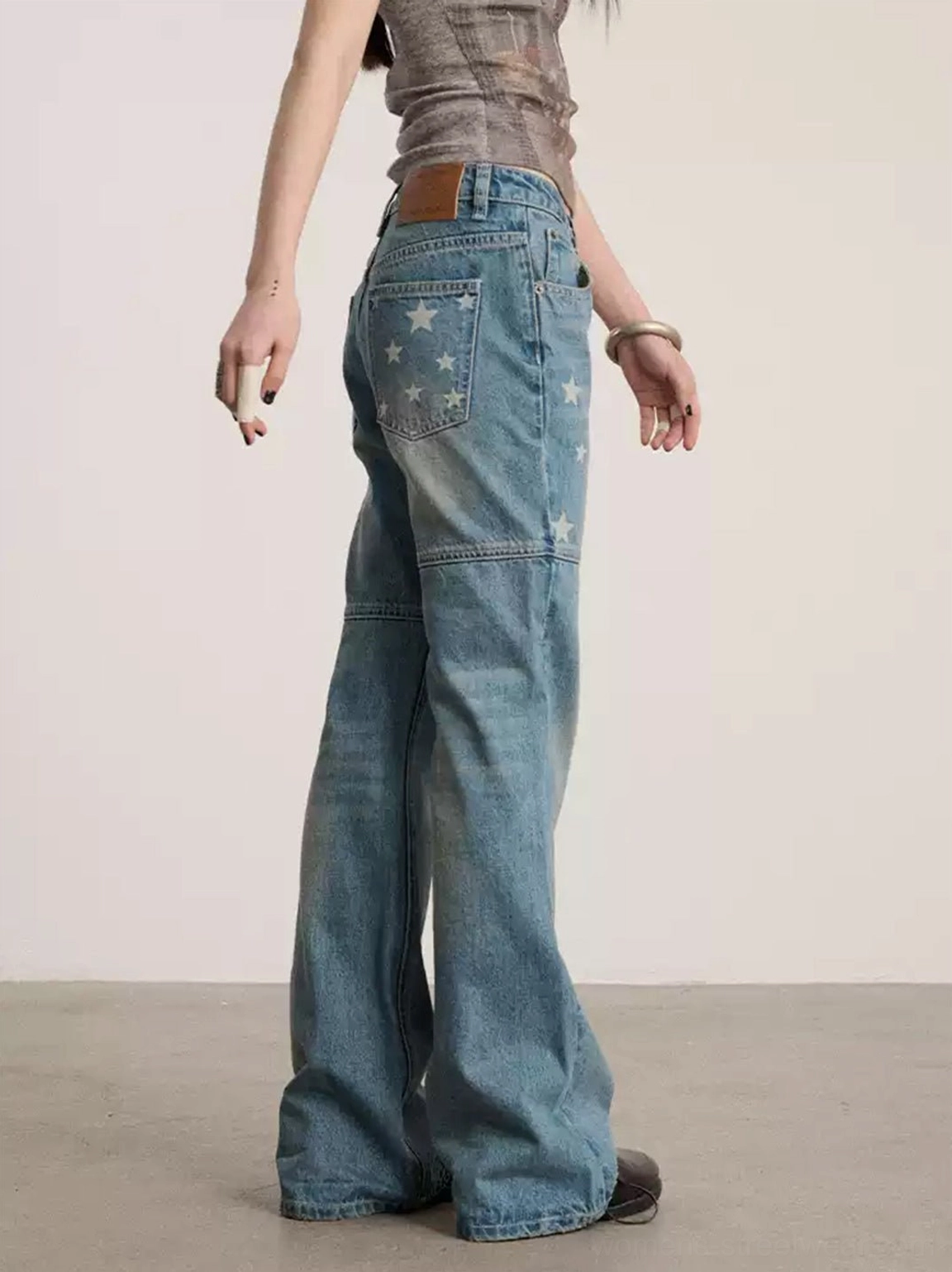 Back view of low-waist blue flare denim jeans with star details on the back pocket, waistband patch, and flared hem