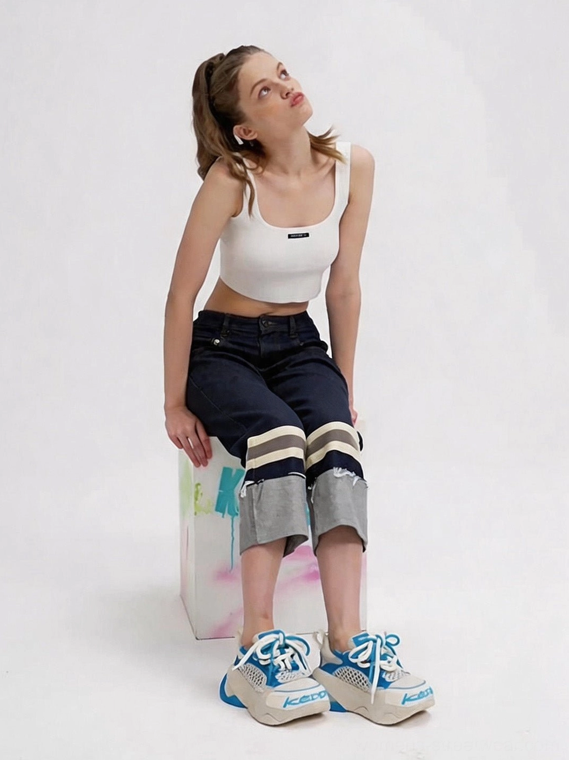 Seated female model wearing macaron blue chunky dad sneakers with breathable mesh panels and a thick speckled sole