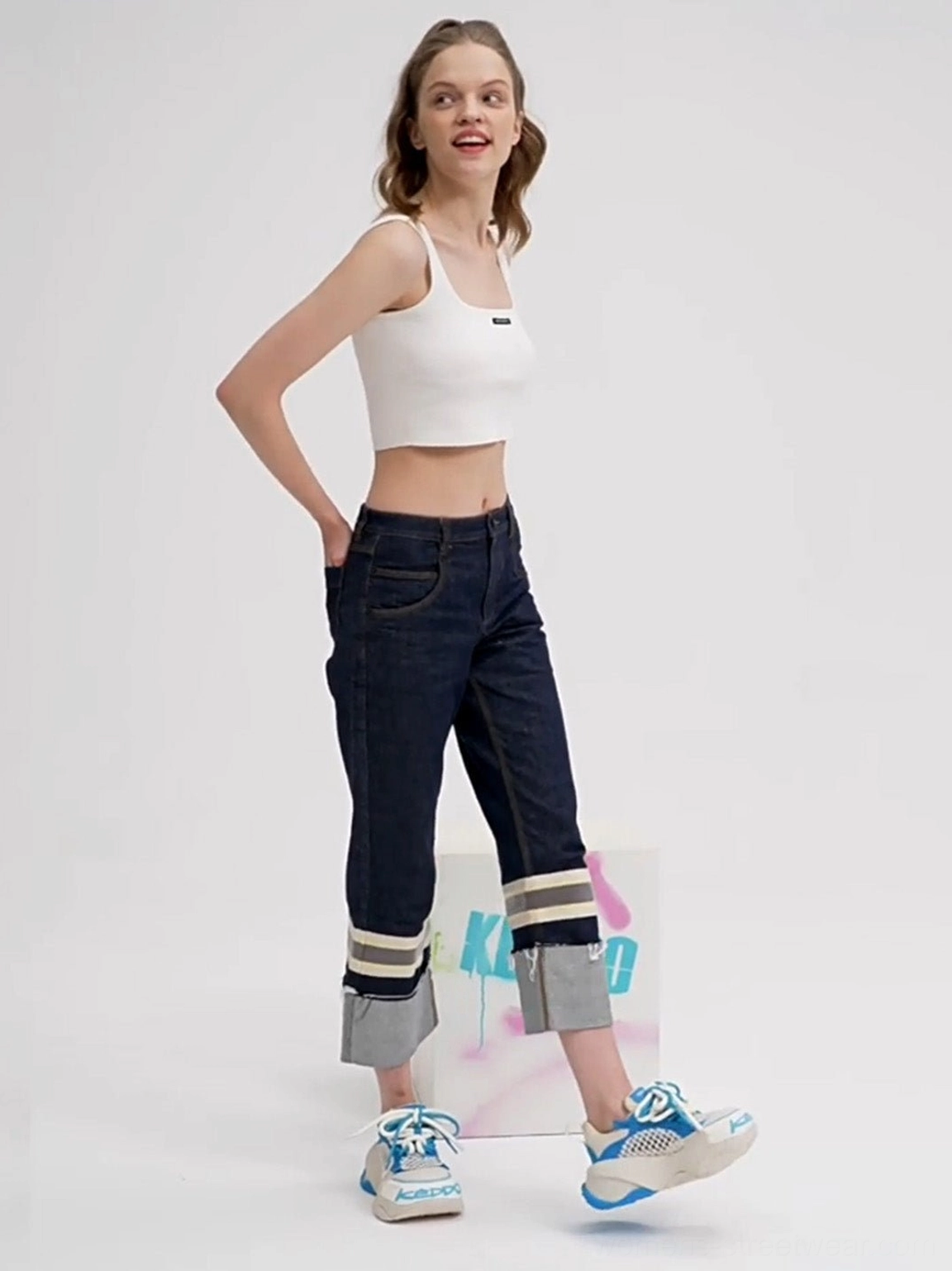 Female model styling blue and white mesh chunky dad sneakers with rolled jeans in three-quarter side view